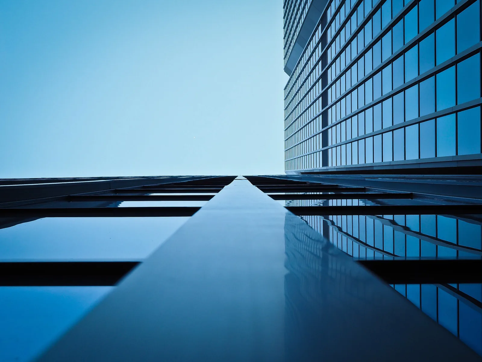 Blue glass office tower rising into a clear sky